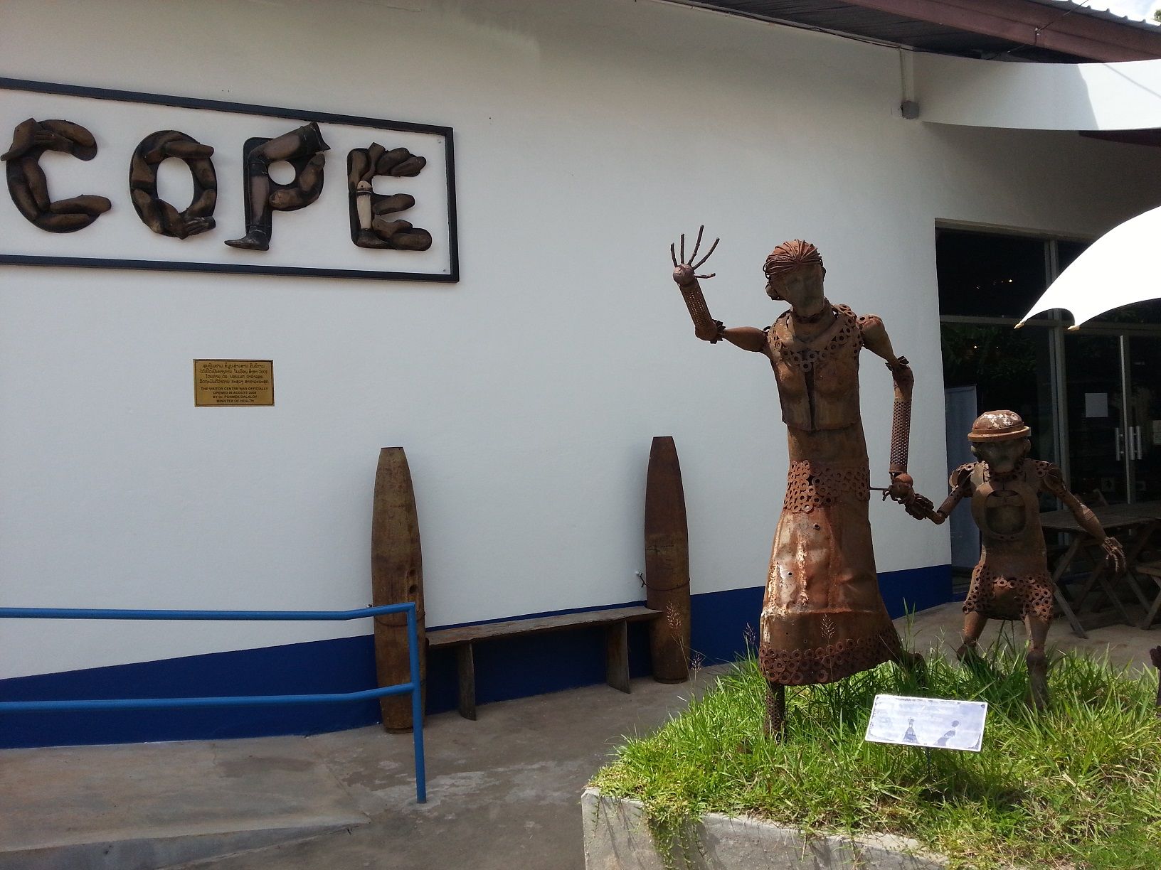 A sculptures of a lady and her child displaying in front of COPE  made from 500kg of UXO including cluster bombs in memories of those who been injured, lost their lives or loved ones  from UXO made by local artist in 2008