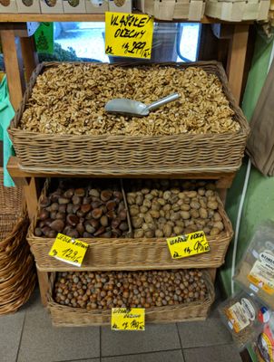Wicker trays of walnuts nuts, edible chestnuts and hazelnuts, with price tags and a metal scoop