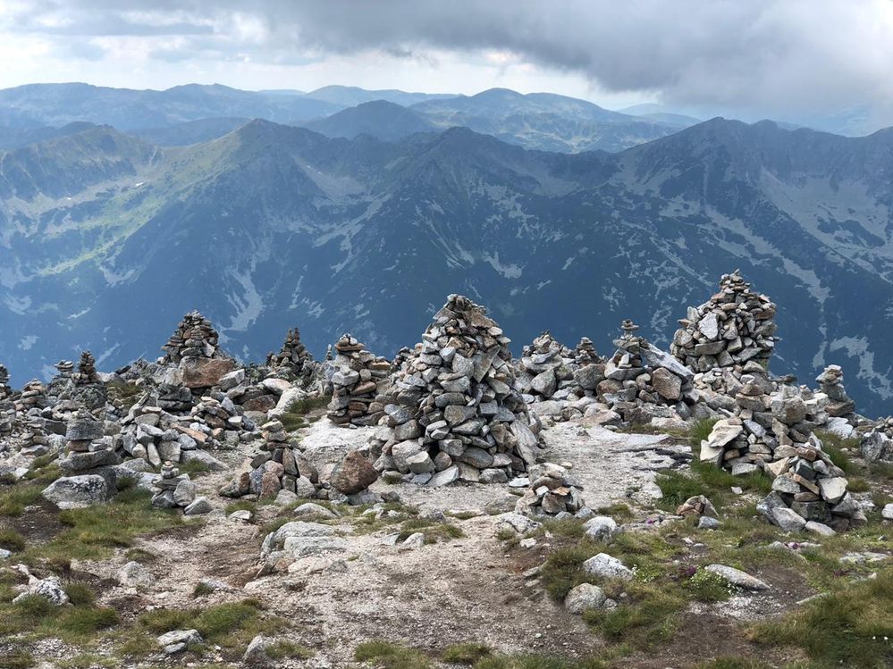 Caption: A photo of rock cairns at the edge of Musala Peak with mountains visible in the background. (Local Guide @FelipePk)